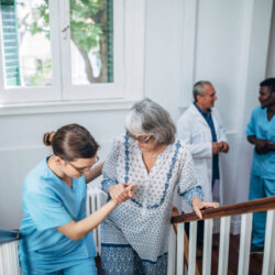 Female nurse supporting senior woman moving up the steps at retirement home